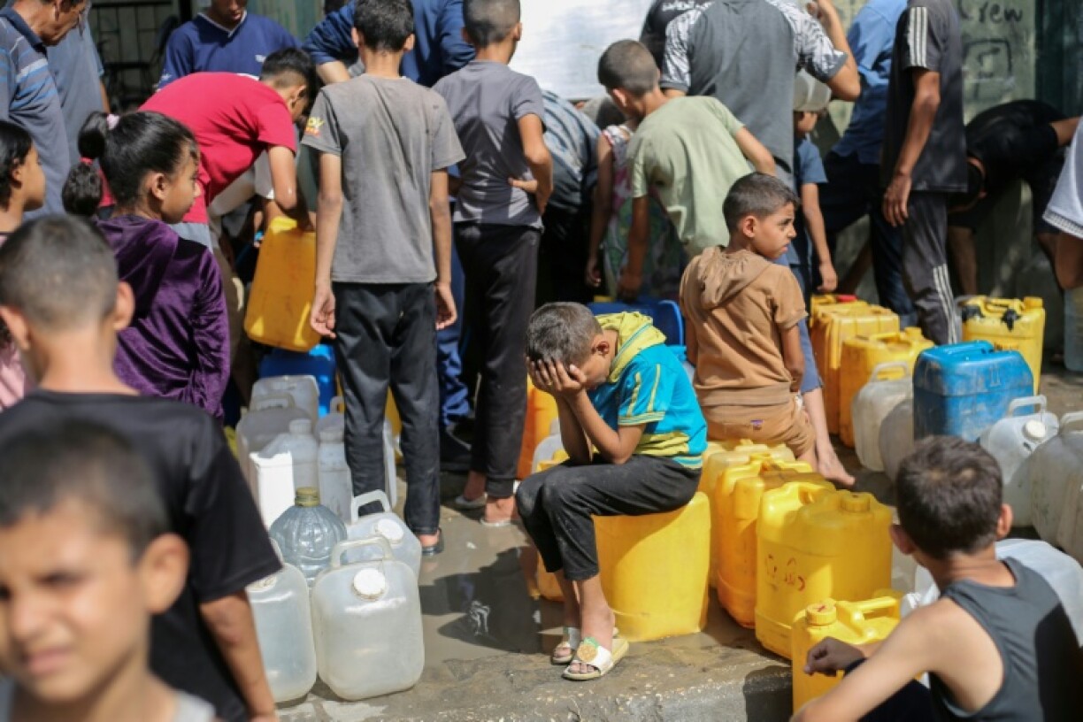 Des enfants palestiniens affluent à une distribution d'eau à Nousseirat, dans le centre de la bande de Gaza, le 4 septembre 2025