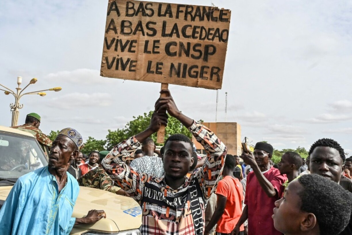Un partisan du Conseil national pour la sauvegarde de la patrie (CNSP) du Niger tient une pancarte lors d'une manifestation devant le Stade Général Seyni Kountche à Niamey, au Niger, le 6 août 2023