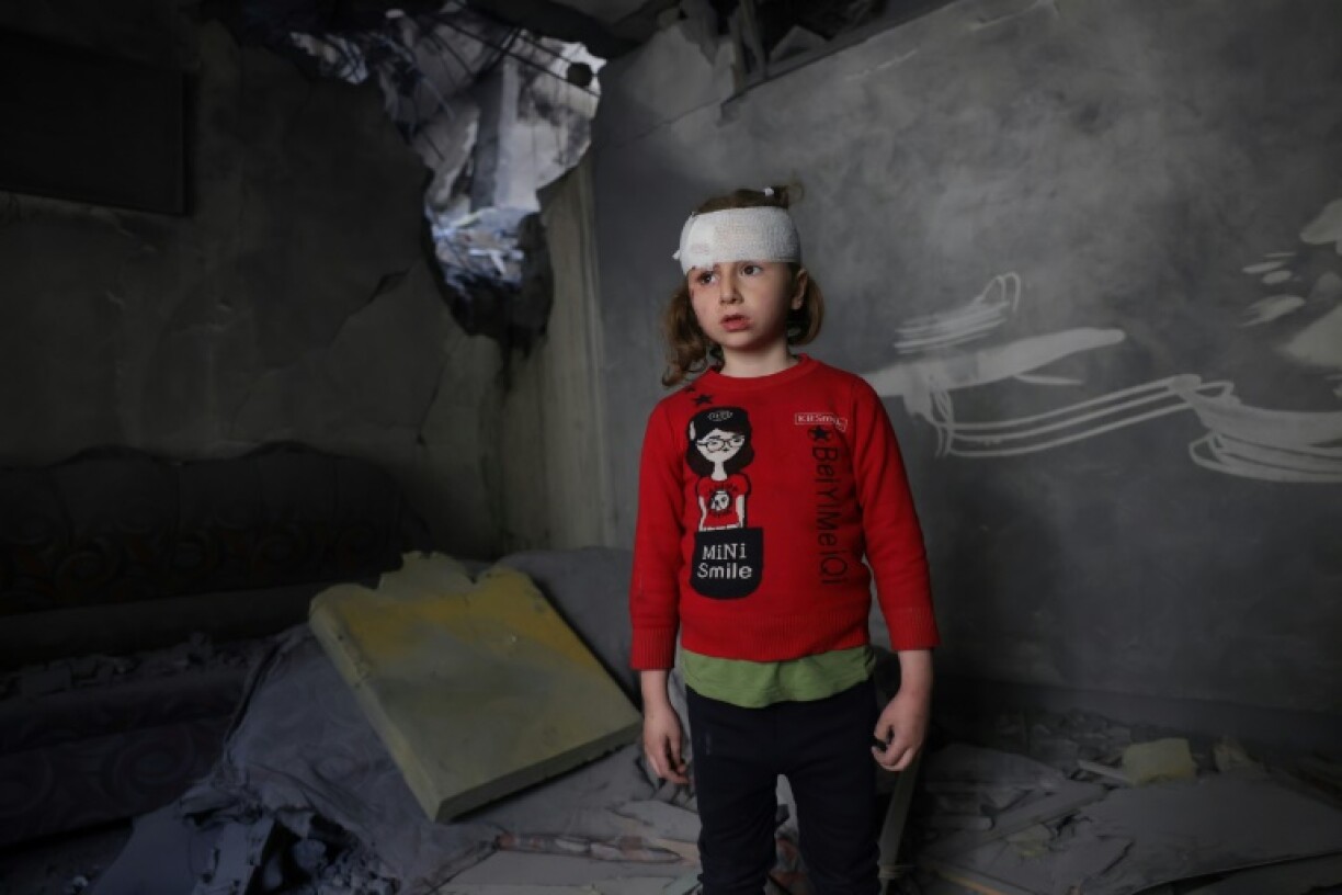 A wounded Palestinian girl stands amid the debris of her family home after overnight Israeli strikes