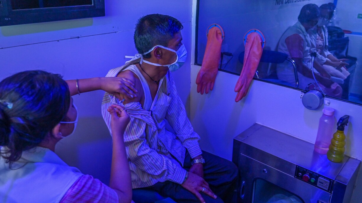 A health worker inoculates a man with a dose of the Covishield vaccine against the Covid-19 coronavirus inside a mobile vaccination van in New Delhi on June 26, 2021.