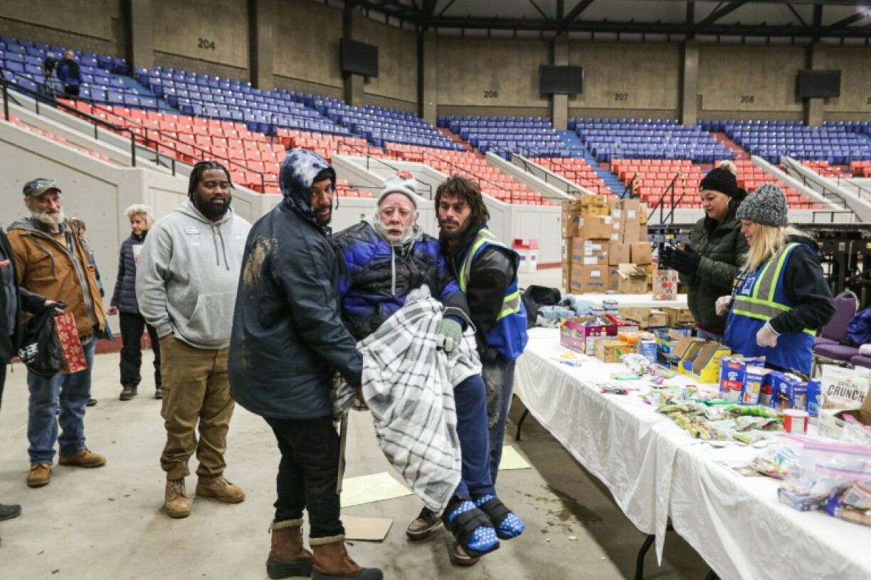 Des bénévoles aident une personne sans-abri à Louisville, dans le Kentucky, dans un refuge ouvert pour faire face à une tempête hivernale, le 23 décembre 2022
