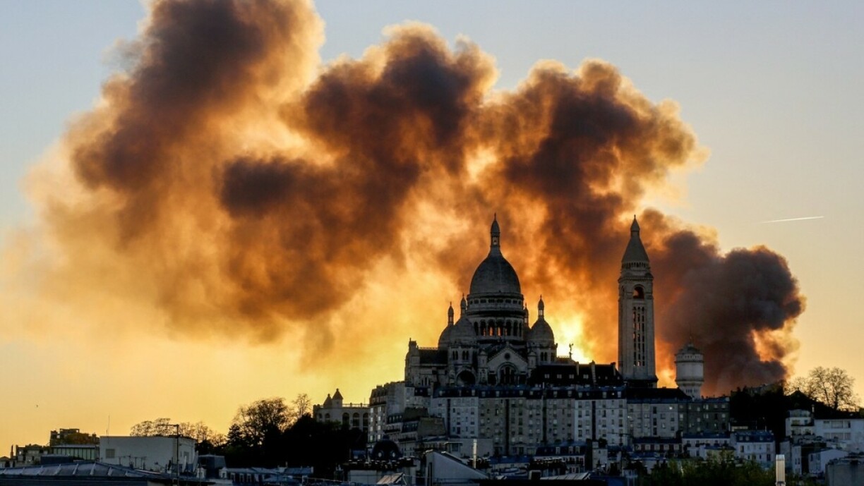 La basilique du Sacré-Cœur devant une colonne de fumée provoquée par l'incendie d'un centre de tri à Paris.