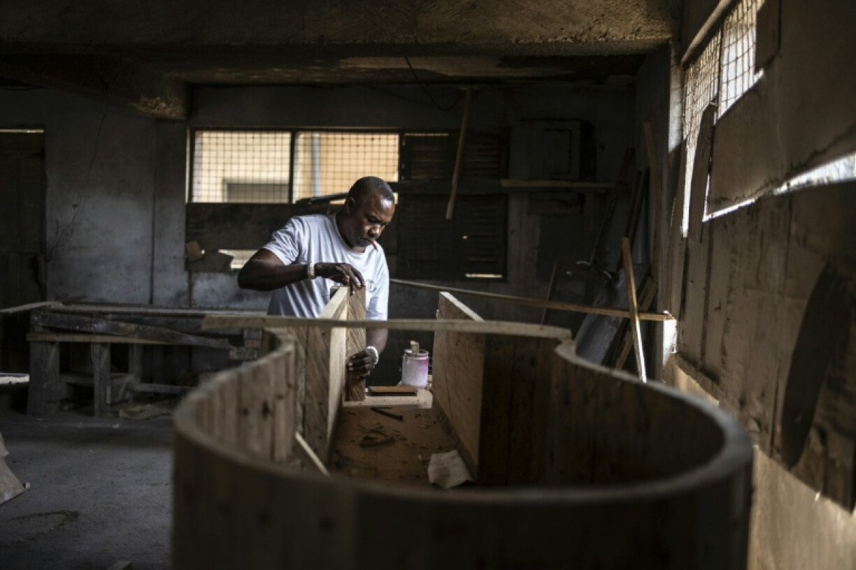 Daniel Oble Mensah, 54 ans, propriétaire de l'atelier Hello Design Coffin Workshop, travaille sur un cercueil en forme de guitare commandé pour un guitariste décédé, dans son atelier d'Accra, au Ghana, le 18 août 2026