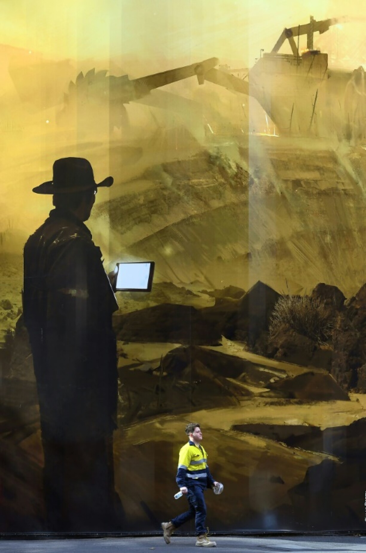 A man walks past a mural of a mine by artist Simon Denny in Melbourne