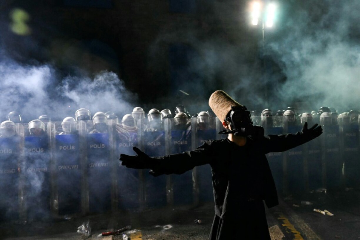 A whirling dervish stands in of front riot police in Istanbul