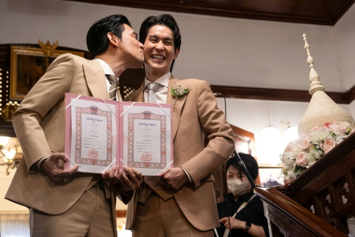 Thai actors Apiwat 'Porsch' Apiwatsayree (L) and Sappanyoo 'Arm' Panatkool pose after registering their same-sex marriage Thursday