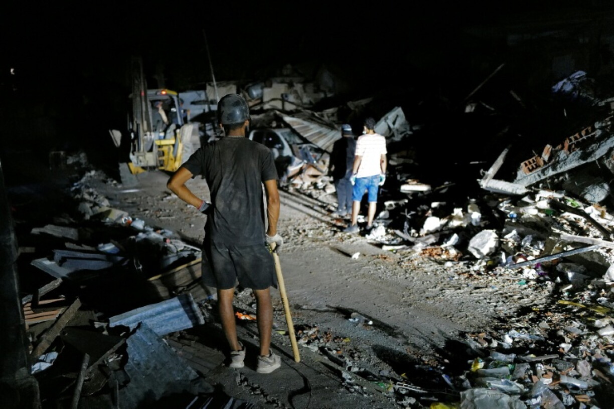 Des secouristes éclairent la zone à l'aide des phares d'un pick-up tout en recherchant d'éventuelles victimes dans un bâtiment effondré à la suite de deux séismes, à Caraballeda, dans l'Etat de La Guaira, au Venezuela, le 27 juin 2026