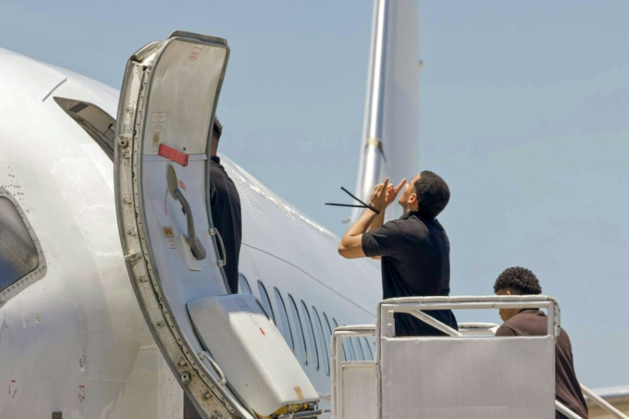 In this handout picture released by El Salvador's presidency, a Venezuelan migrant who was jailed in El Salvador gestures as he boards a plane bound for Venezuela