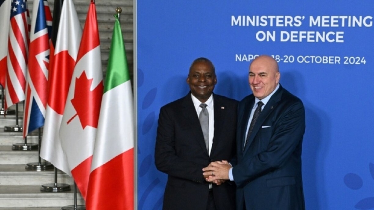 Le ministre italien de la Défense Guido Crosetto (D) et son homologue américain Lloyd Austin se serrent la main pendant la cérémonie d'accueil d'un G7 Défense à Naples, en Italie, le 19 octobre 2024