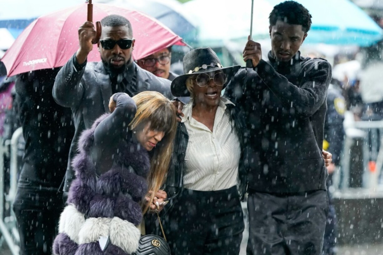 King Combs (R), son of Sean Combs, holds an umbrella for Janice Combs, mother of Sean Combs, as they arrive at federal court for Sean