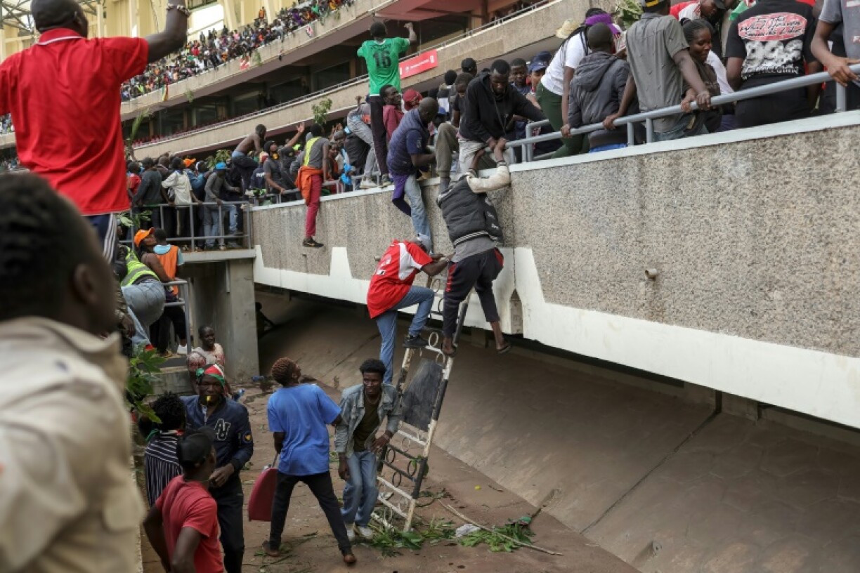 Kenyans run for cover as security forces fire in a stadium where they gathered to view the coffin of Raila Odinga