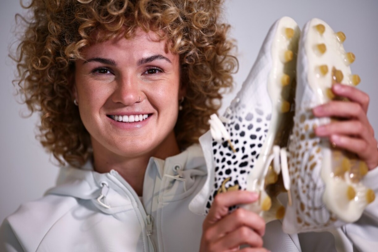 England's Ellie Kildunne poses with the boots she helped design and will wear in a Women's Rugby World Cup semi-final against France