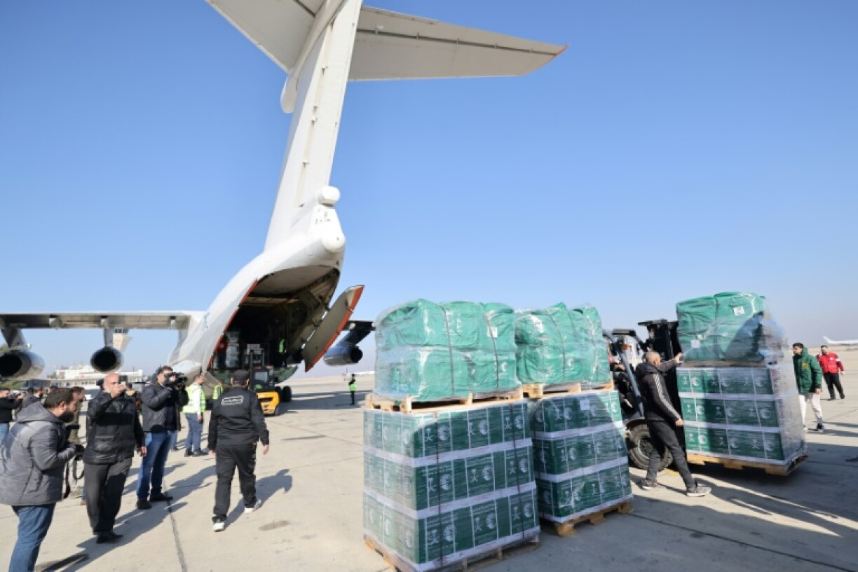 Workers unload humanitarian aid supplied by Saudi Arabia at the airport in Damascus; a high-ranking Syrian delegation has traveled to Saudi Arabia on the first foreign visit by the country's new Islamist rulers