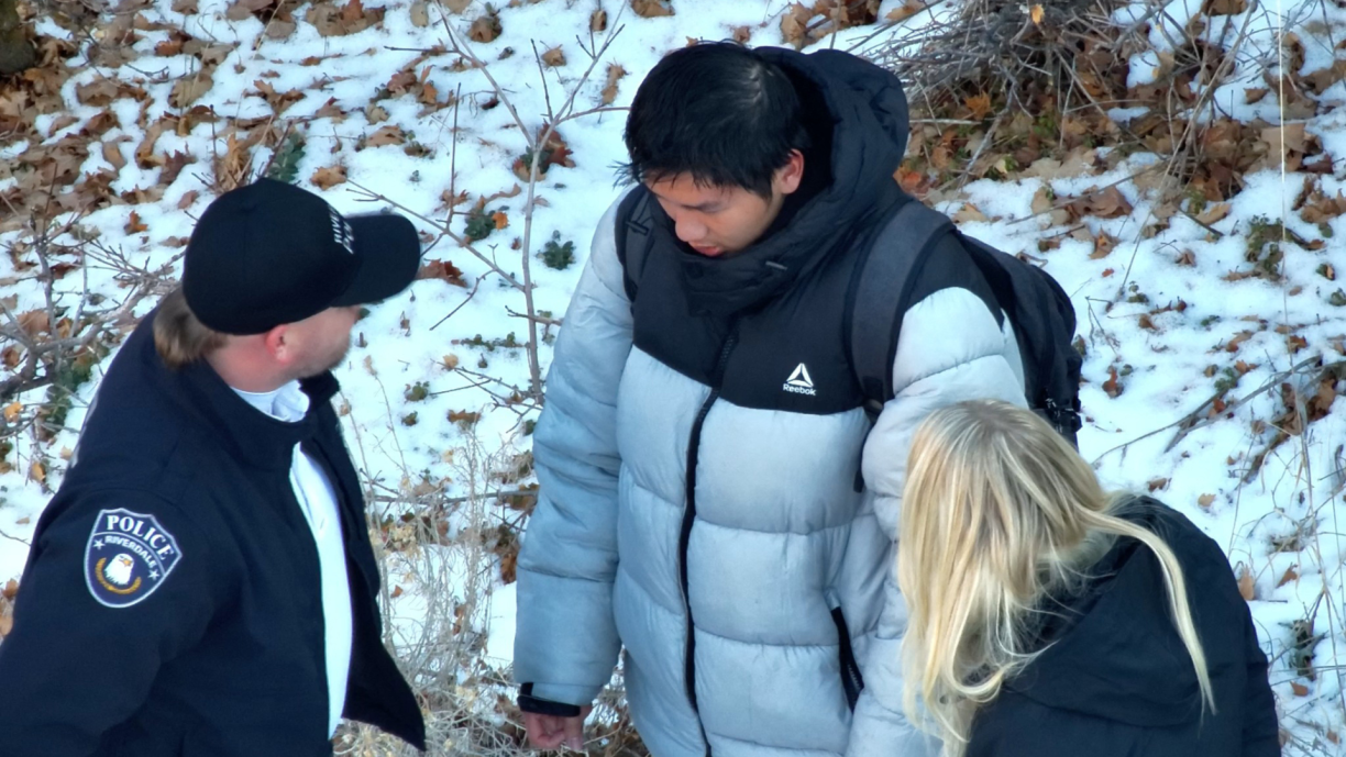 This handout photo released by the Riverdale Police Department on January 1, 2024 shows authorities speaking to Kai Zhuang near the site where he was found in the mountains near Brigham City, Utah, on December 31, 2023, after being reported missing. A Chinese exchange student who fell victim to a
