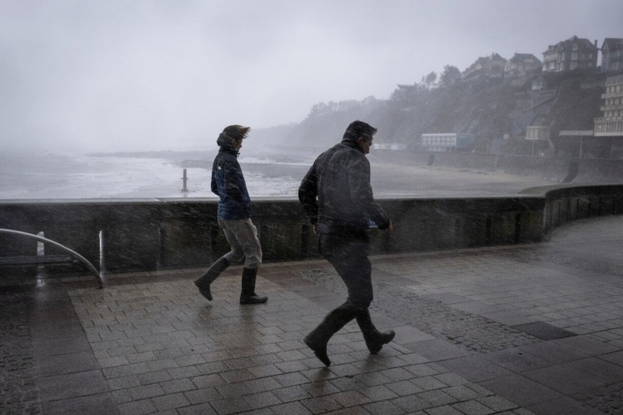 Des promeneurs pris dans les bourrasques de la tempête Austen sur le front de mer à Granville, dans la Manche, le 23 octobre 2026