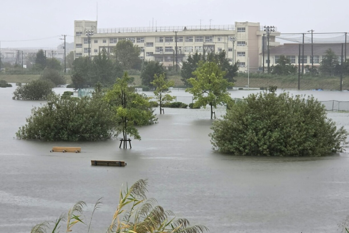 Des piétons traversent une route inondée sous une pluie battante, à l'approche du typhon Dujuan, à Funabashi, dans la préfecture de Chiba, le 21 septembre 2026 au Japon