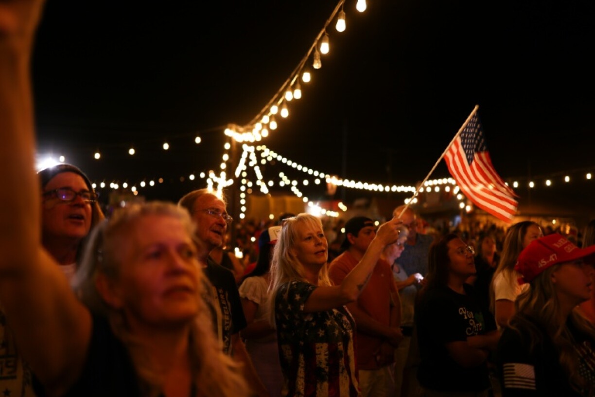 A woman waves a US flag during a candlelight vigil in memory of right-wing activist Charlie Kirk in Morristown, Arizona