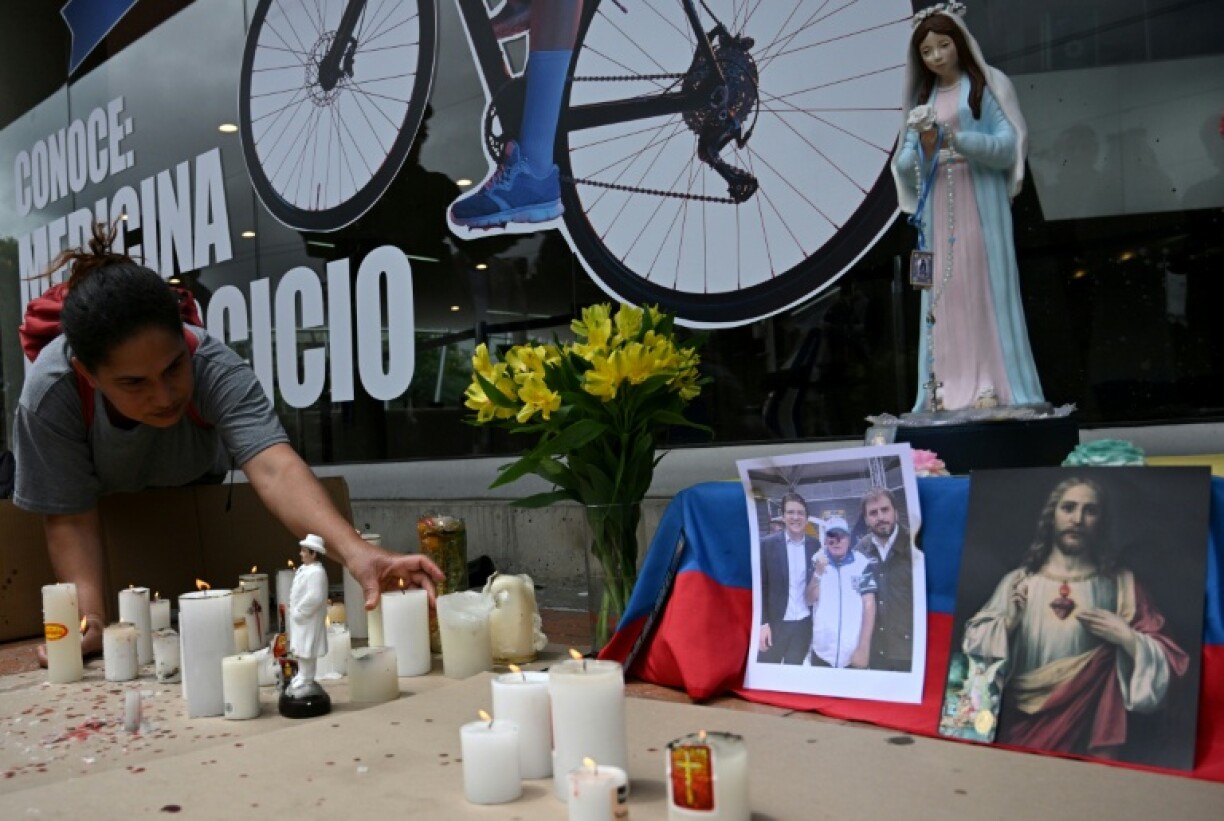 A woman lights candles at a makeshift altar outside the Fundacion Santa Fe clinic, where Colombian presidential candidate Miguel Uribe is hospitalized after being shot during a political event in Bogota on June 10, 2025.