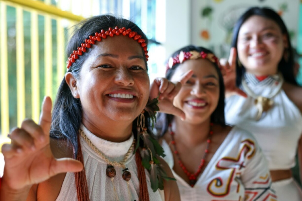 Indigenous Kambeba women supporting Brazil's President Luiz Inacio Lula da Silva make an 'L' gesture with their hands while queueing to vote during the presidential election