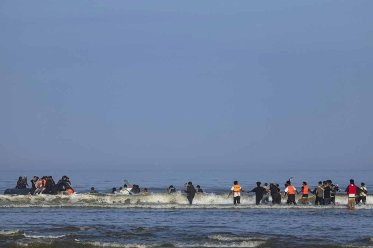 Migrants try to board a smuggler's boat to cross the Channel, from the beach of Equihen, northern France, on June 30, 2025