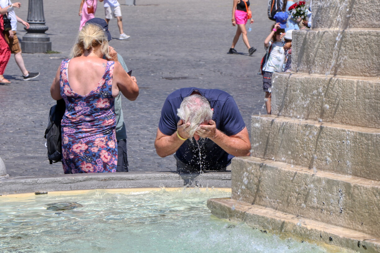 En Tourist erfrëscht sech bei grousser Hëtzt un engem Buer.