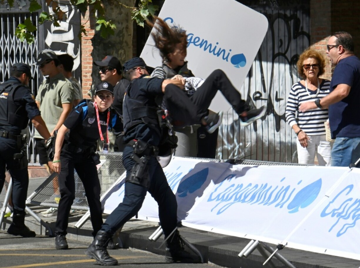 A police officer detains a woman as Pro-Palestinians protesters demonstrate while cyclists compete during the 18th stage of the Vuelta a Espana