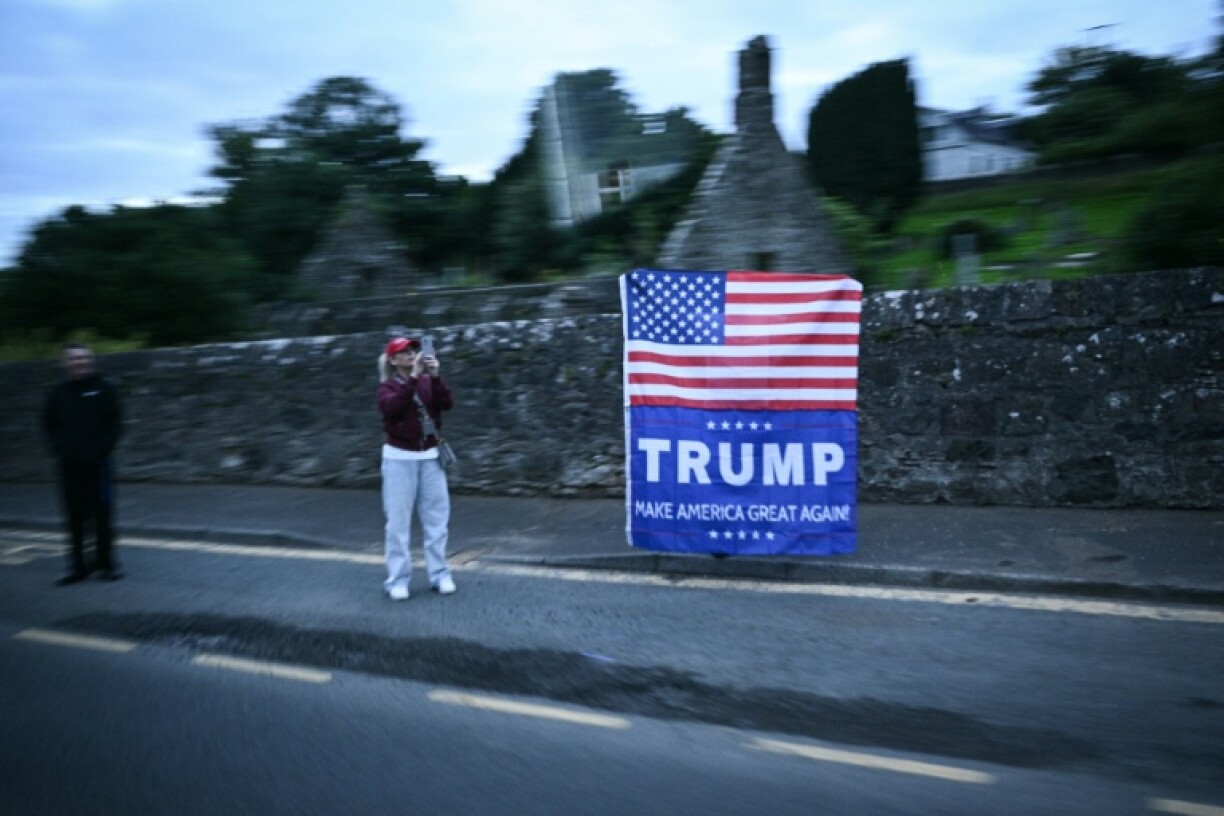 People welcome Trump with a giant US flag as US president Donald Trump delegations drive past them near Prestwick airport