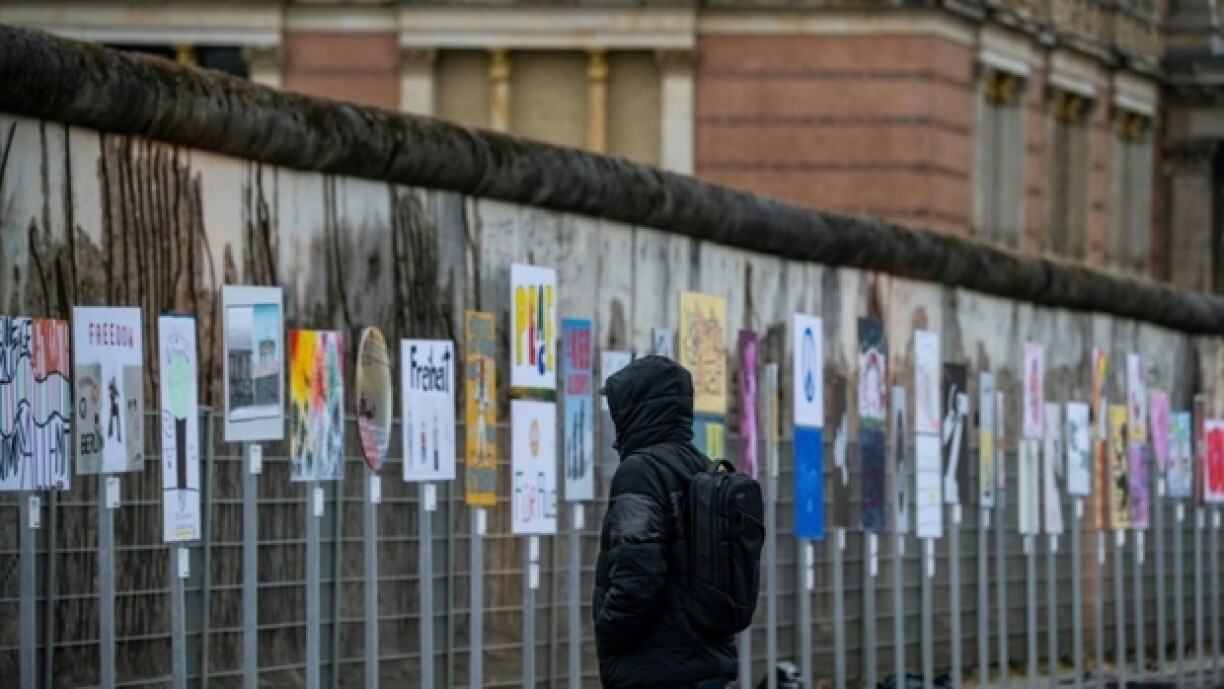 Un homme regarde des pancartes installées le long de l'ancien tracé du Mur de Berlin vendredi 8 novembre, en vue des célébrations des 35 ans de la chute du Mur de Berlin, intervenue le 9 novembre 1989
