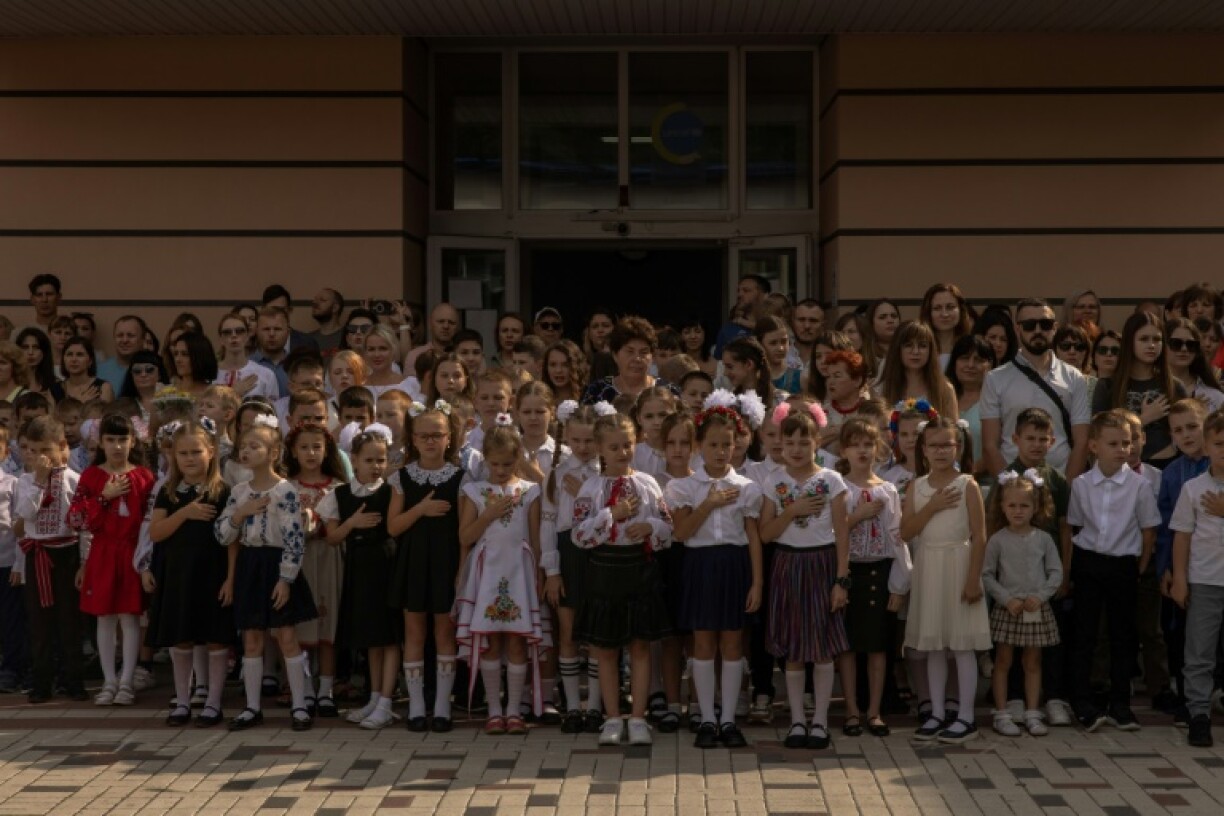 Des enfants ukraniens chantent l'hymne national avec leurs enseignants et leurs familles lors de la rentrée des classes, le 1er septembre 2023 à Irpin, dans les environs de Kiev