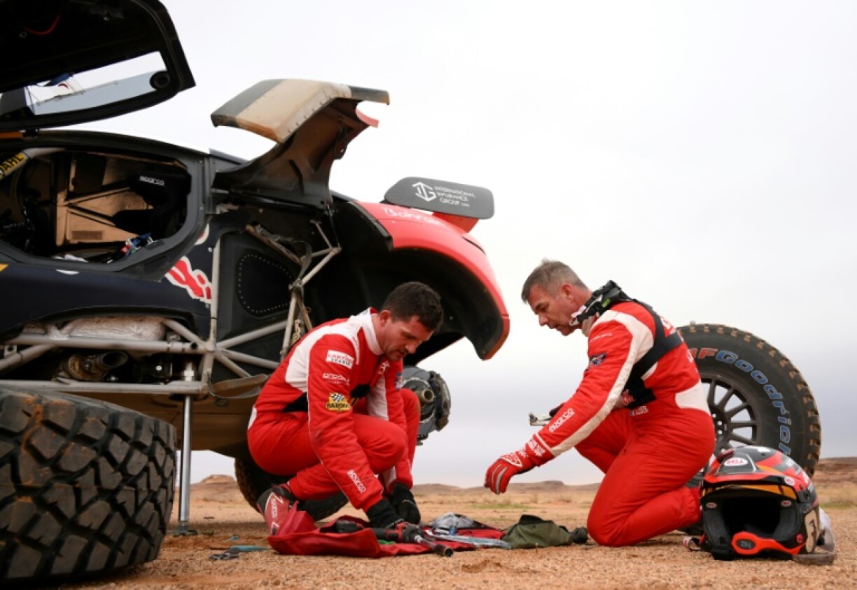 Le pilote français Sébastien Loeb et son copilote belge Fabian Lurquin (à gauche) changent un pneu durant la 3e étape du Dakar, en Arabie saoudite, le 3 janvier 2023