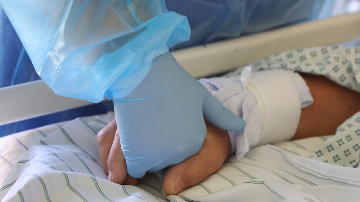 A doctor holds the hand of a Covid-19 patient in the Covid-19 intensive care unit of the community hospital (Klinikum Magdeburg) in Magdeburg, eastern Germany, on April 28, 2021, amid the novel coronavirus COVID-19 pandemic.