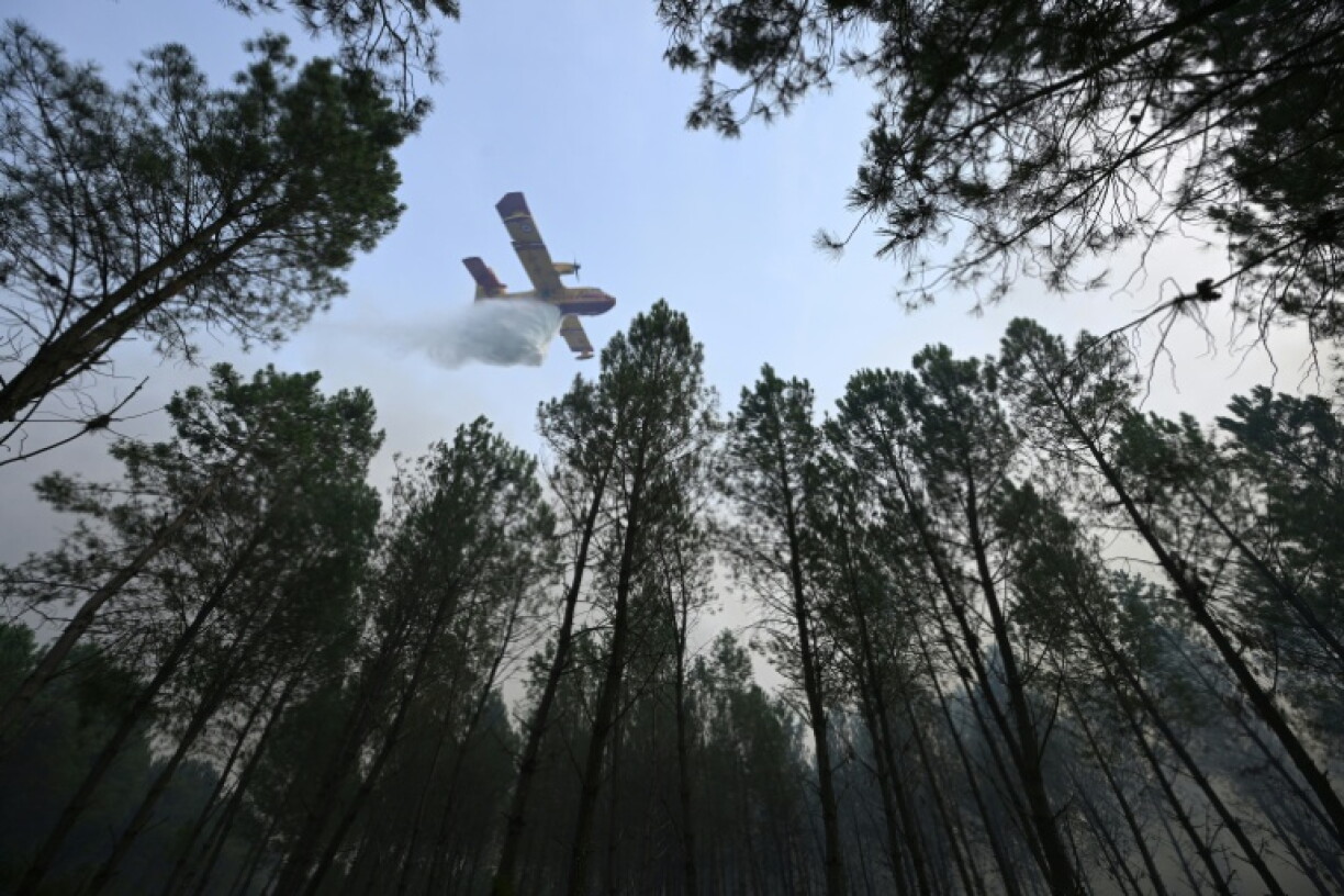 Un avion de lutte contre les incendies CL-415 de la Sécurité civile française, de type Canadair, déverse de l'eau sur les arbres d'une forêt lors d'un incendie de forêt à Luglon, dans le sud-ouest de la France, le 14 août 2026