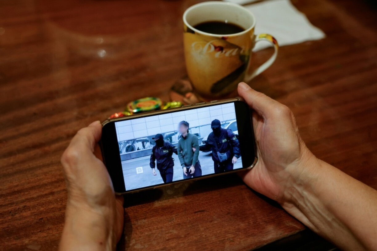 A person watches a news feed running a Russia's FSB security service footage of the operation to detain a Japanese journalist accused of espionage, on a smartphone in Moscow on October 13, 2026