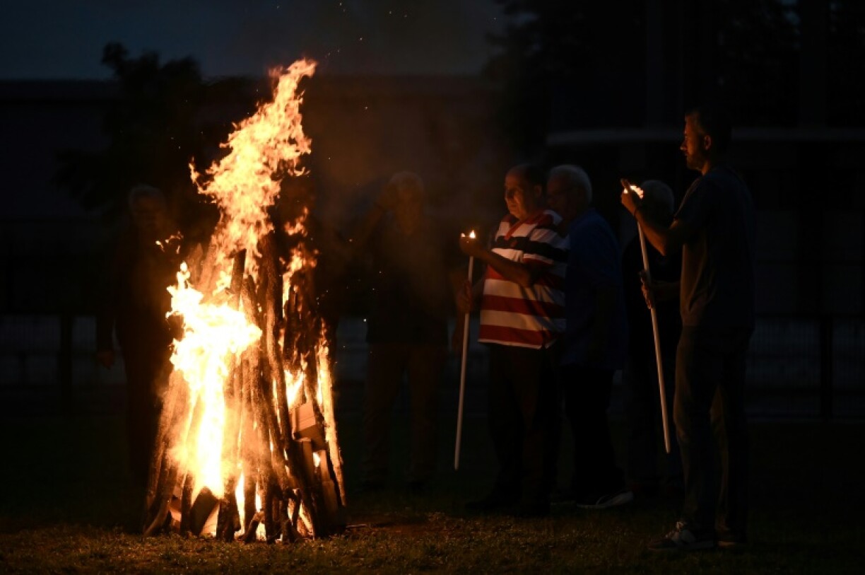 Men light a fire to prepare the burning embers before a select group of faithful known as 'anastenarides' walk across the hot coals