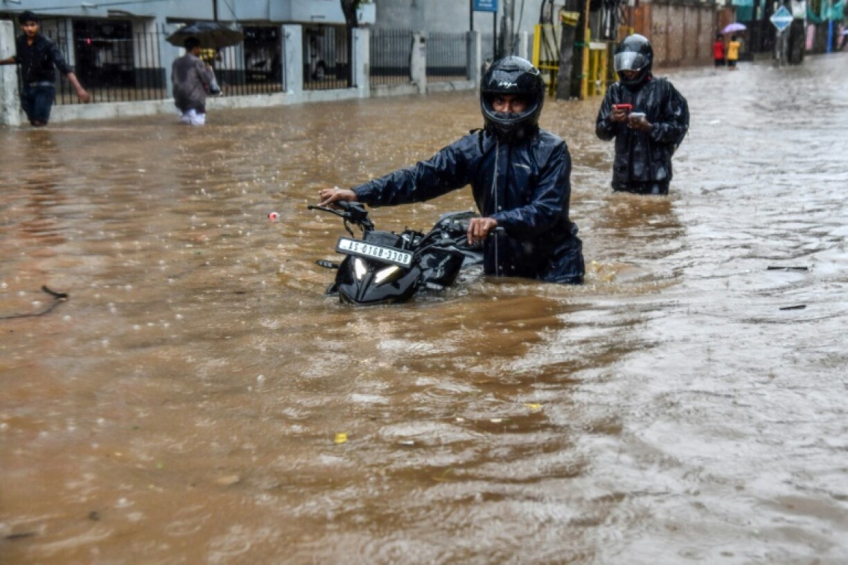 Residents wade through a flooded street after heavy rainfall in Guwahati, in India's state of Assam on May 30