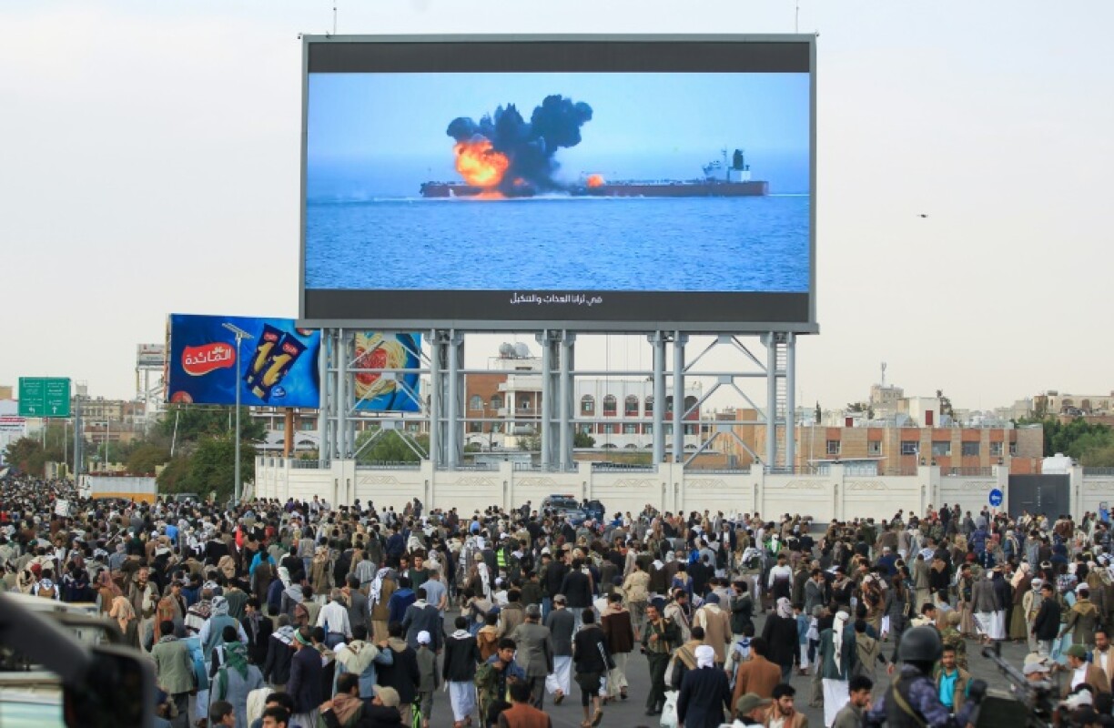 Images of a fireball exploding on a cargo ship are shown on a giant screen during a protest in Sanaa