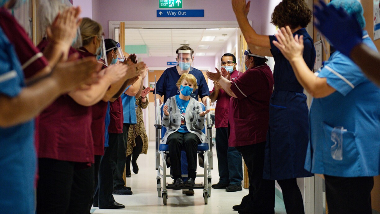 Margaret Keenan (C), 90, is applauded by staff as she returns to her ward after becoming the first person to receive the Pfizer-BioNtech Covid-19 vaccine at University Hospital in Coventry, central England, on December 8, 2020. Britain on December 8 hailed a turning point in the fight against the coronavirus pandemic, as it begins the biggest vaccination programme in the country's history with a new Covid-19 jab.