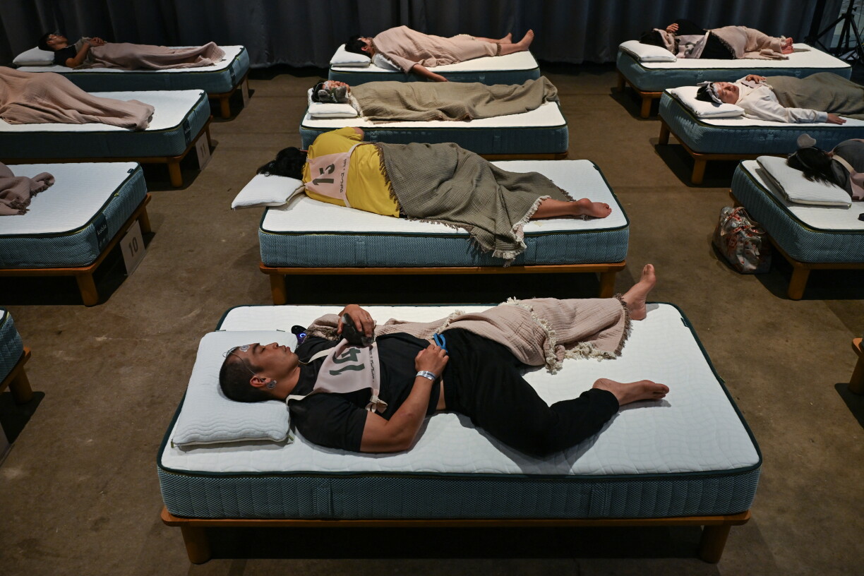 TOPSHOT - Attendees take part in a sleep competition organized by a mattress brand in Tokyo on October 5, 2026. (Photo by Selim CHTAYTI / AFP)