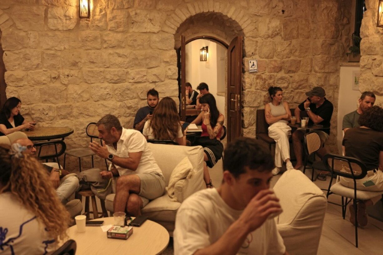 Des Israéliens attablés dans le café Basimta, alors que manifestants ultra-orthodoxes protestent contre l'ouverture durant le shabbat, jour de repos hebdomadaire juif et que des militants laïques organisent une contre-manifestation à Jérusalem, le 15 août 2026.