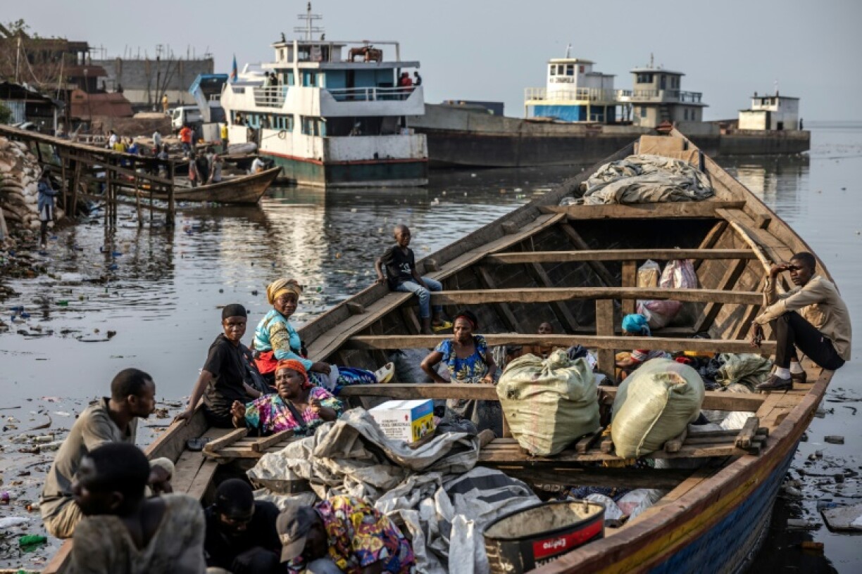 Families wait in a boat with their belongings on the shores of Lake Kivu in Bukavu as thousands flee the conflict