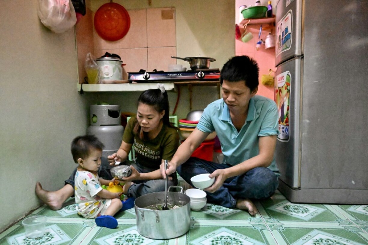Truong Thi Le, who works at a Taiwanese-owned shoe factory, has dinner with her husband and daughter inside their apartment in Ho Chi Minh City
