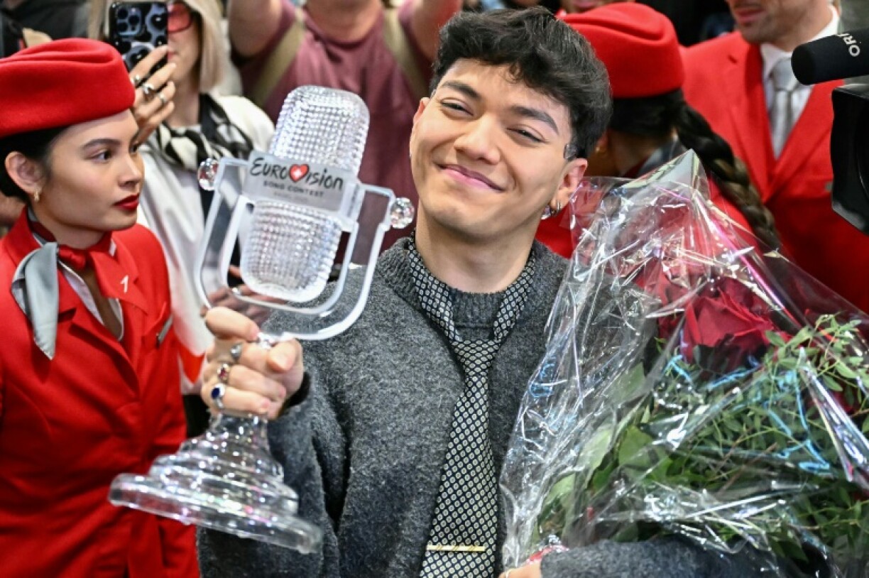 The smiling winner stepped off the plane clutching a bouquet of red roses and his trophy