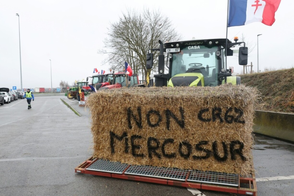 Une botte de foin "Non au Mercosur" sur un tracteur alors que des agriculteurs participent à un blocage sur l'autoroute A1 près de Fresnes-lès-Montauban, le 12 janvier 2026 dans le Pas-de-Calais