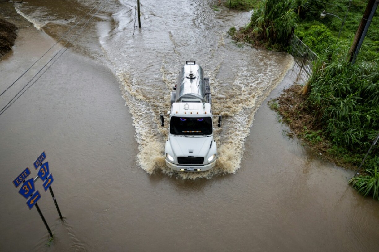 A truck drives through a flooded road as Category 3 Hurricane Erin leaves the region in Naguabo, Puerto Rico