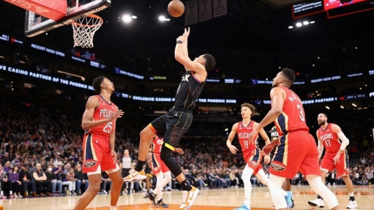L'arrière des Phoenix Suns Devin Booker s'impose dans la raquette au milieu de plusieurs joueurs des Pelicans de la Nouvelle-Orléans, le 17 décembre 2022 à Phoenix