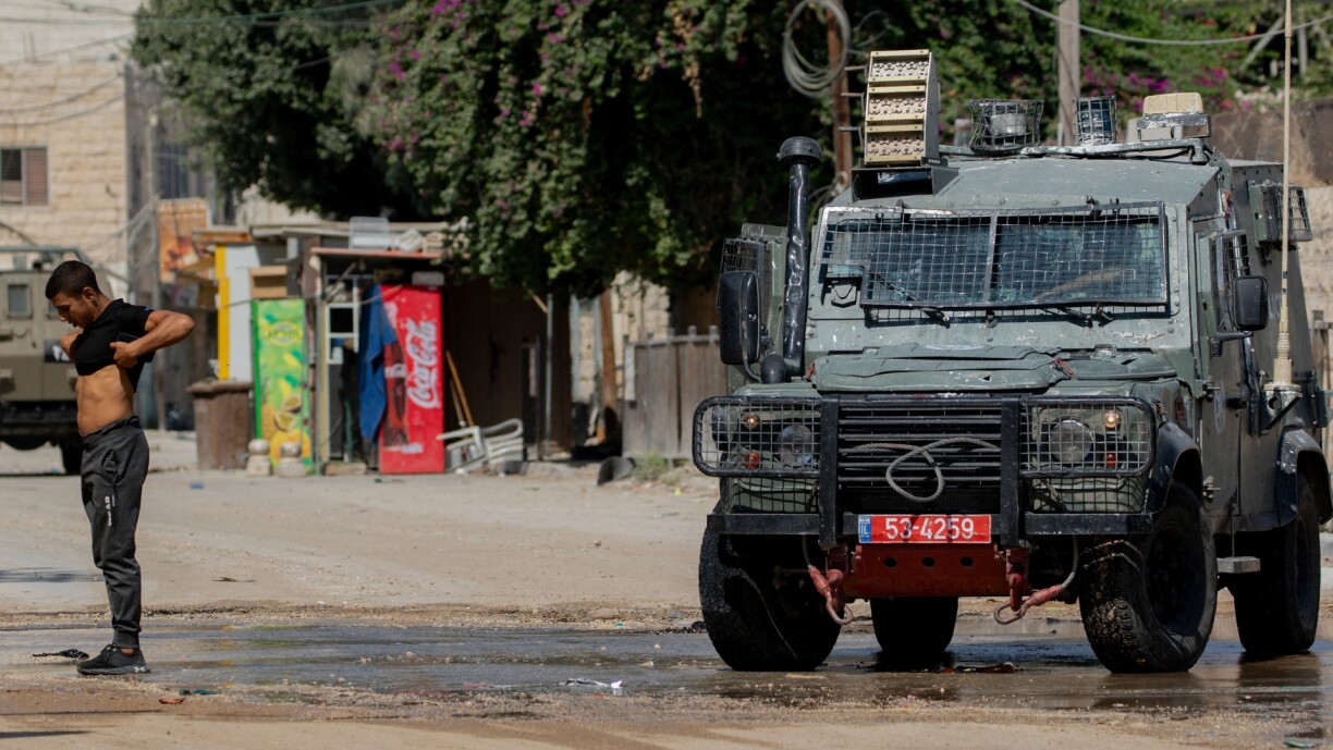 A Palestinian youth lifts his t-shirt up to show Israeli troops that he is unarmed during a military operation in Jenin in the north of the occupied West Bank on 29 August 2024.