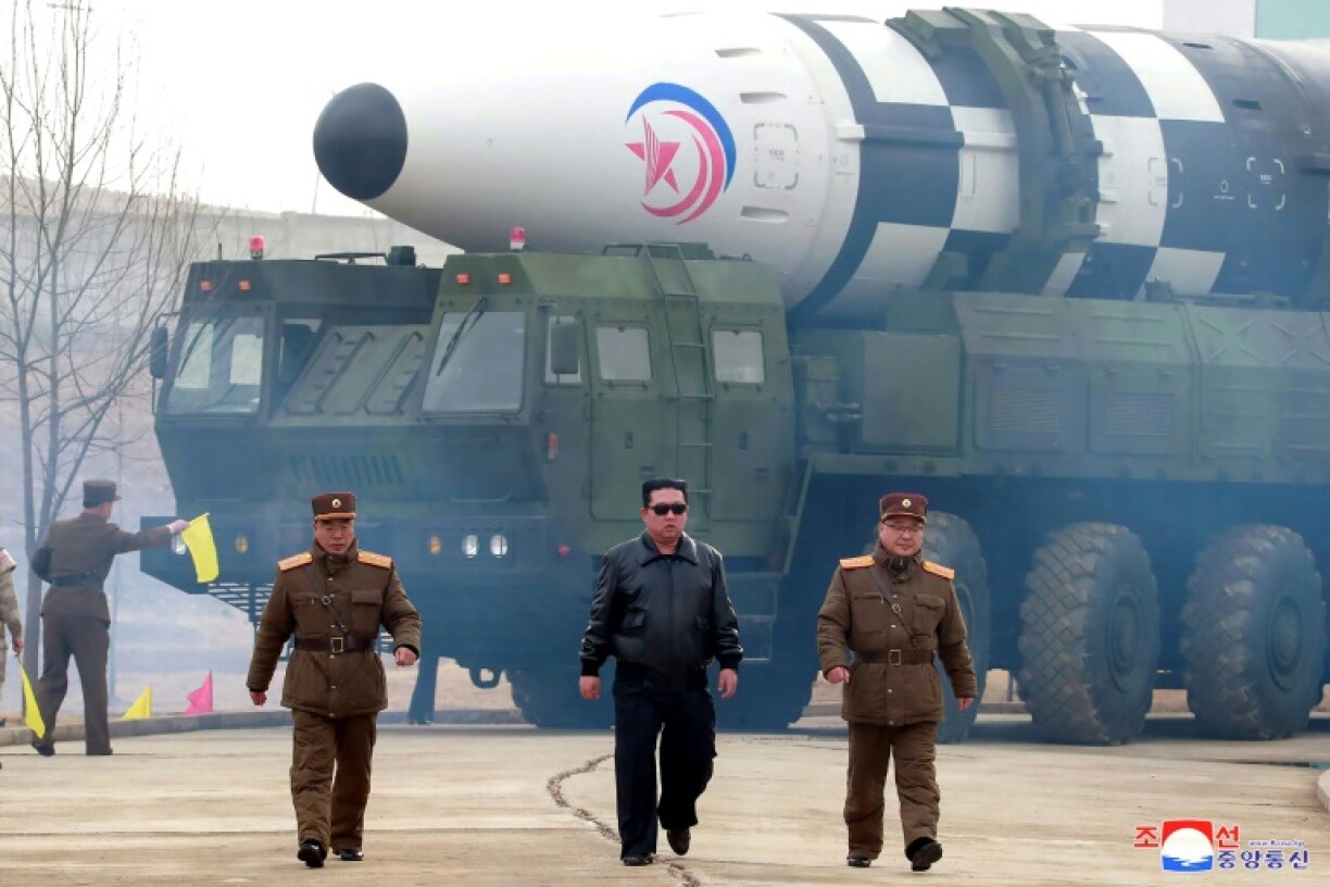 Le dirigeant nord-coréen Kim Jong Un (centre) marche devant ce que les médias d'Etat nord-coréens affirment être un missile balistique intercontinental Hwasong-17 dans un lieu non précisé en Corée du Nord, le 24 mars 2022