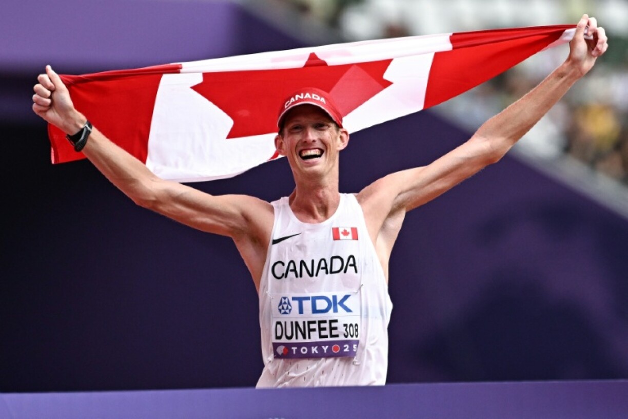Canada's Evan Dunfee crosses the finish line with a Canadian flag to win the men's 35km race walk