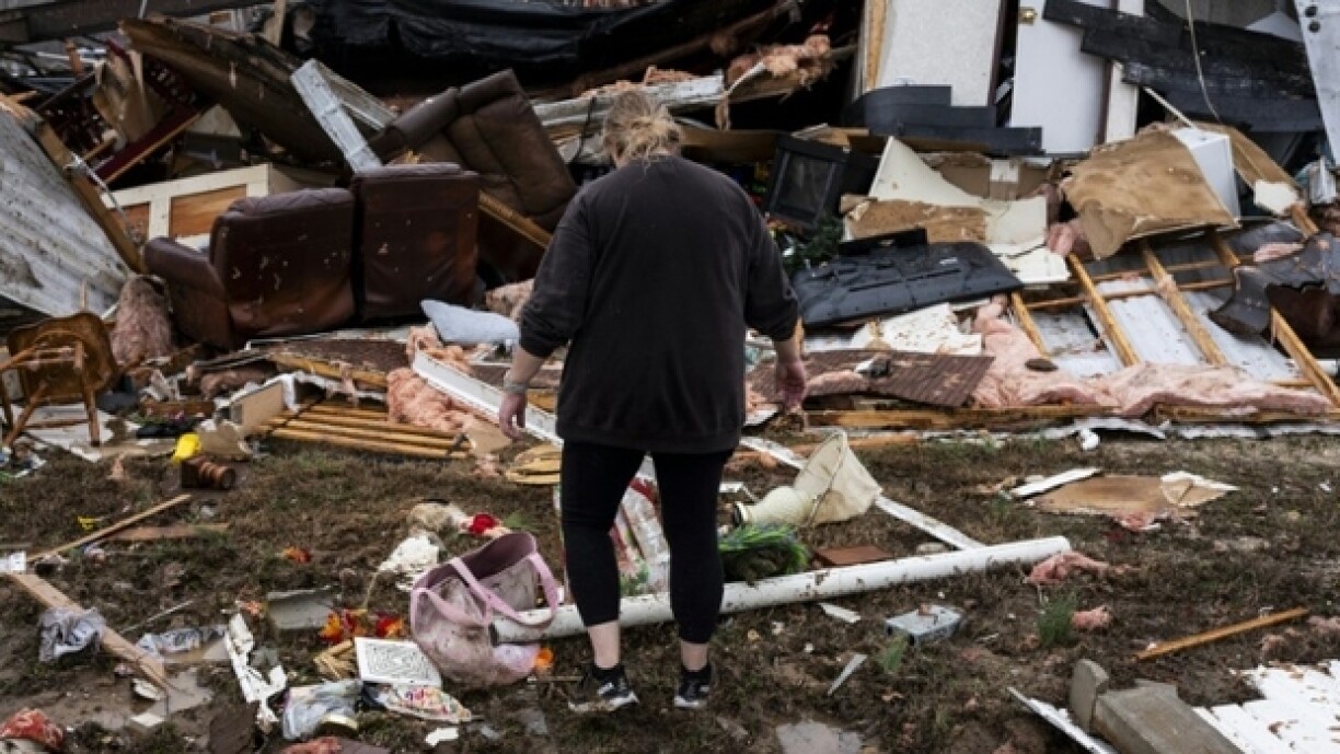 Une sinistrée inspecte sa caravane détruite par les tempêtes, le 15 mars 2025 à Poplar Bluff, dans le Missouri
