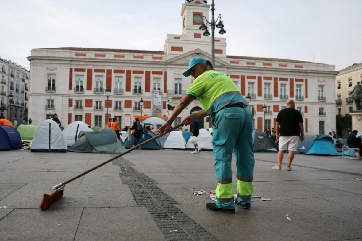 A municipal cleaning service's employee sweeps Madrid's Puerta del Sol square where housing activists have camped out
